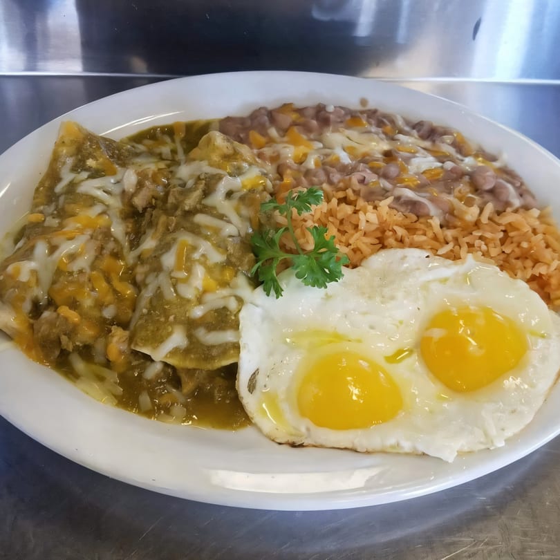 Jerry's Cafe enchiladas with green sauce, cheese, rice, beans, and two fried eggs.